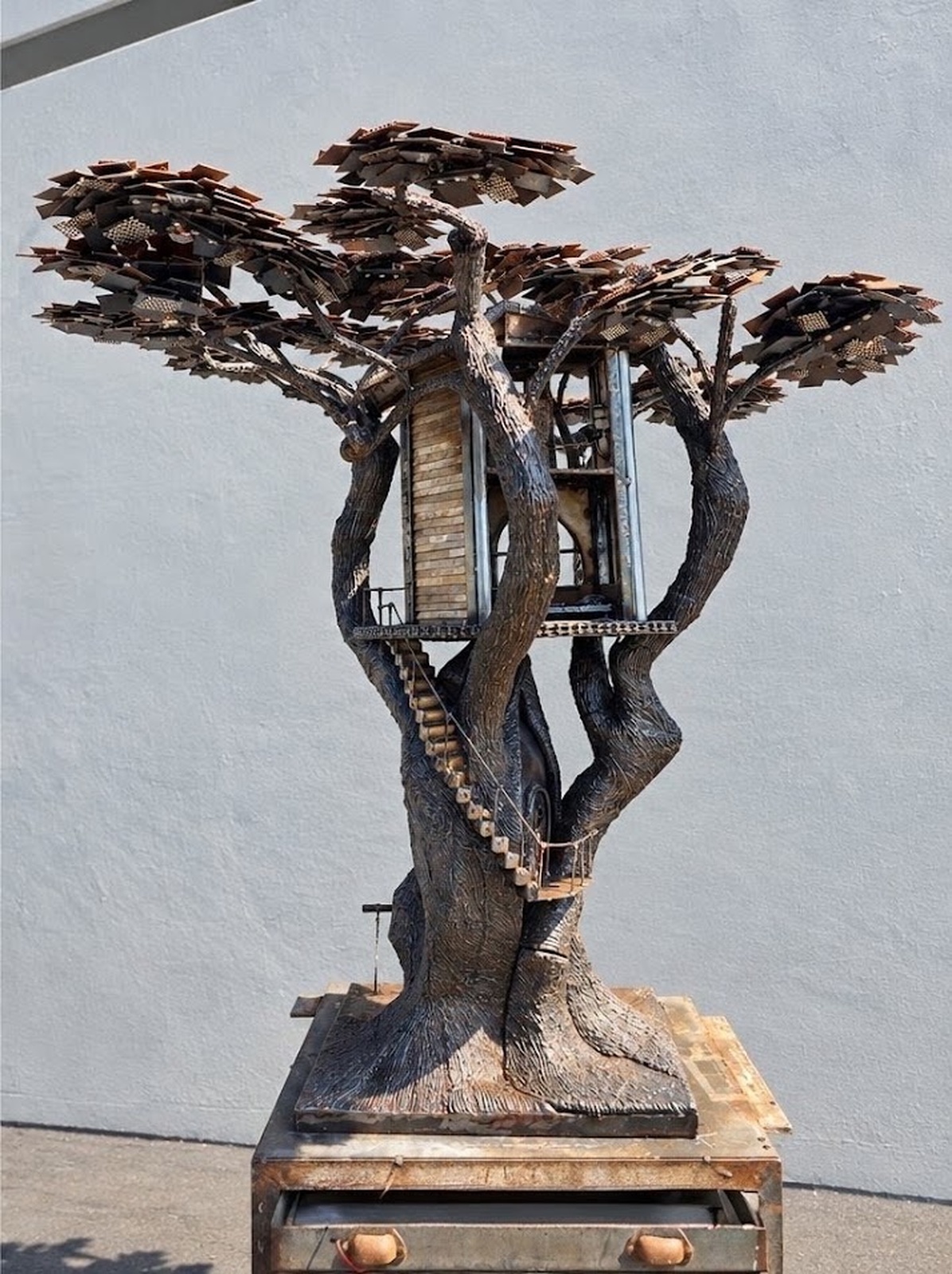 Opposite side view of Heaven on Earth showing the steel tree form, house structure, branches, and open spaces through the sculpture.