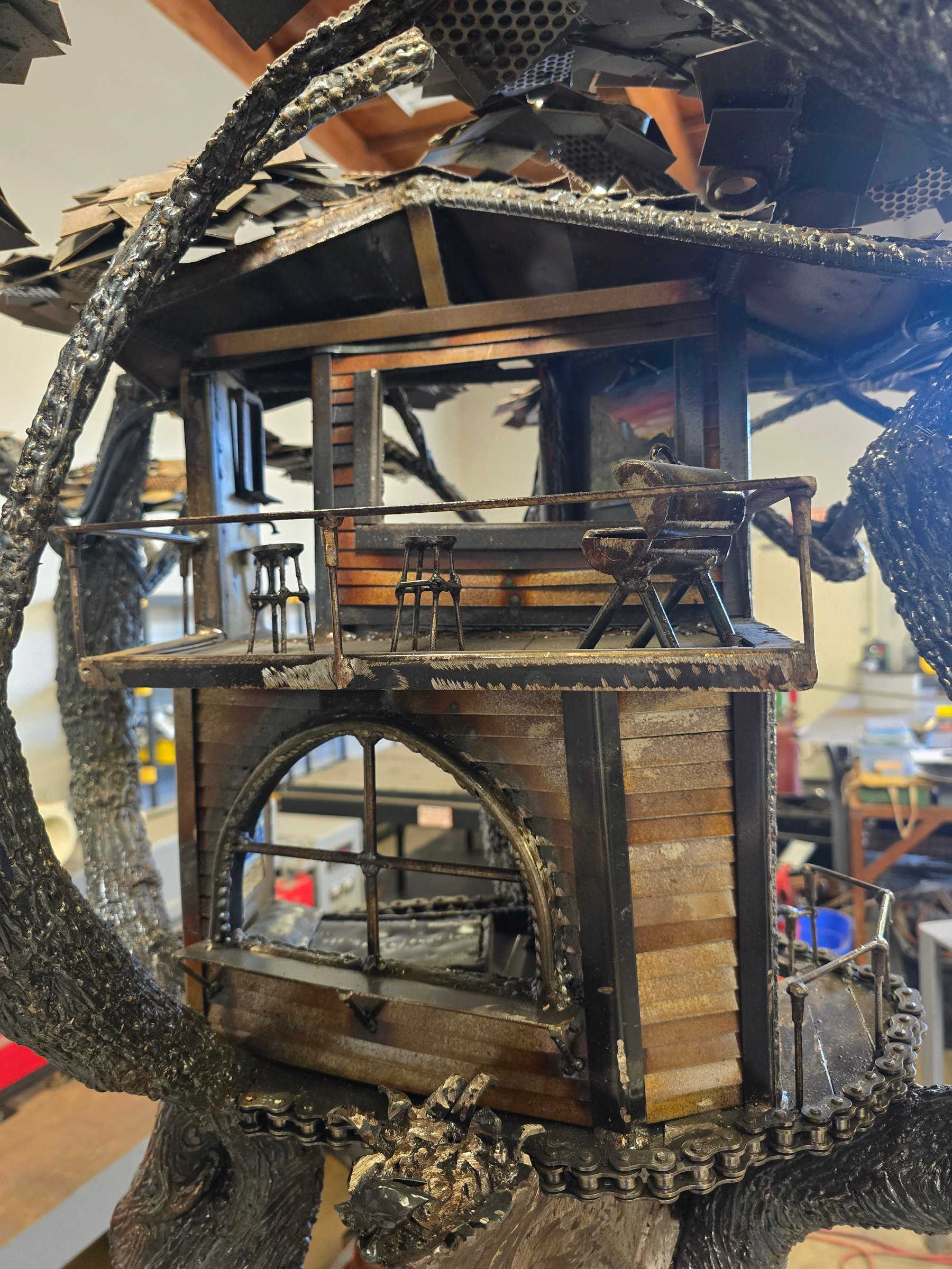Close view of the house in Heaven on Earth showing the deck, railings, windows, roof structure, and hand-built steel details.